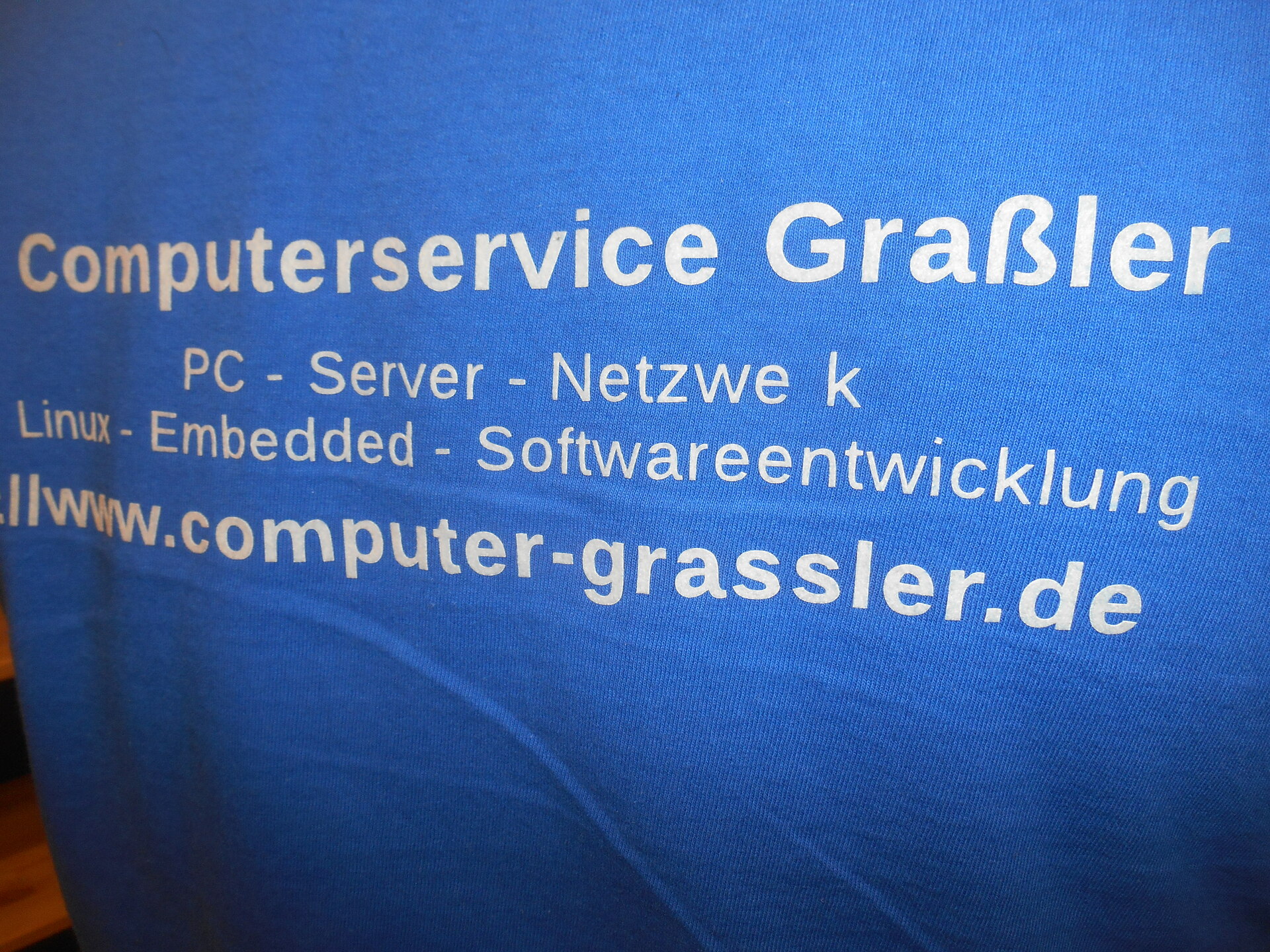 Firmenhemd von Computer Grassler, beim Wort "Netzwerk" fehlt das 'r'.